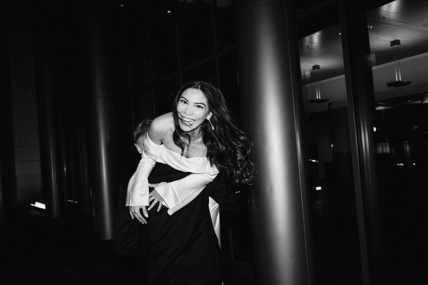 Dramatic black and white portrait in evening formal wear against dark column.