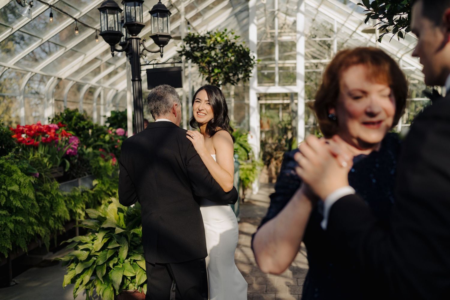 Wedding celebration captured in a bright greenhouse filled with colorful flowers and festive atmosphere.