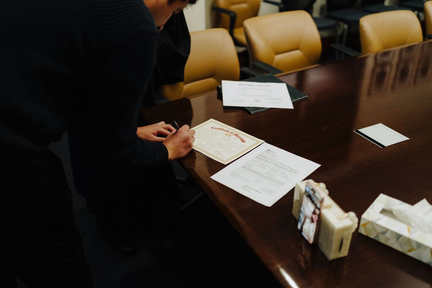 Close-up view of paperwork and documents spread across dark wooden conference table.