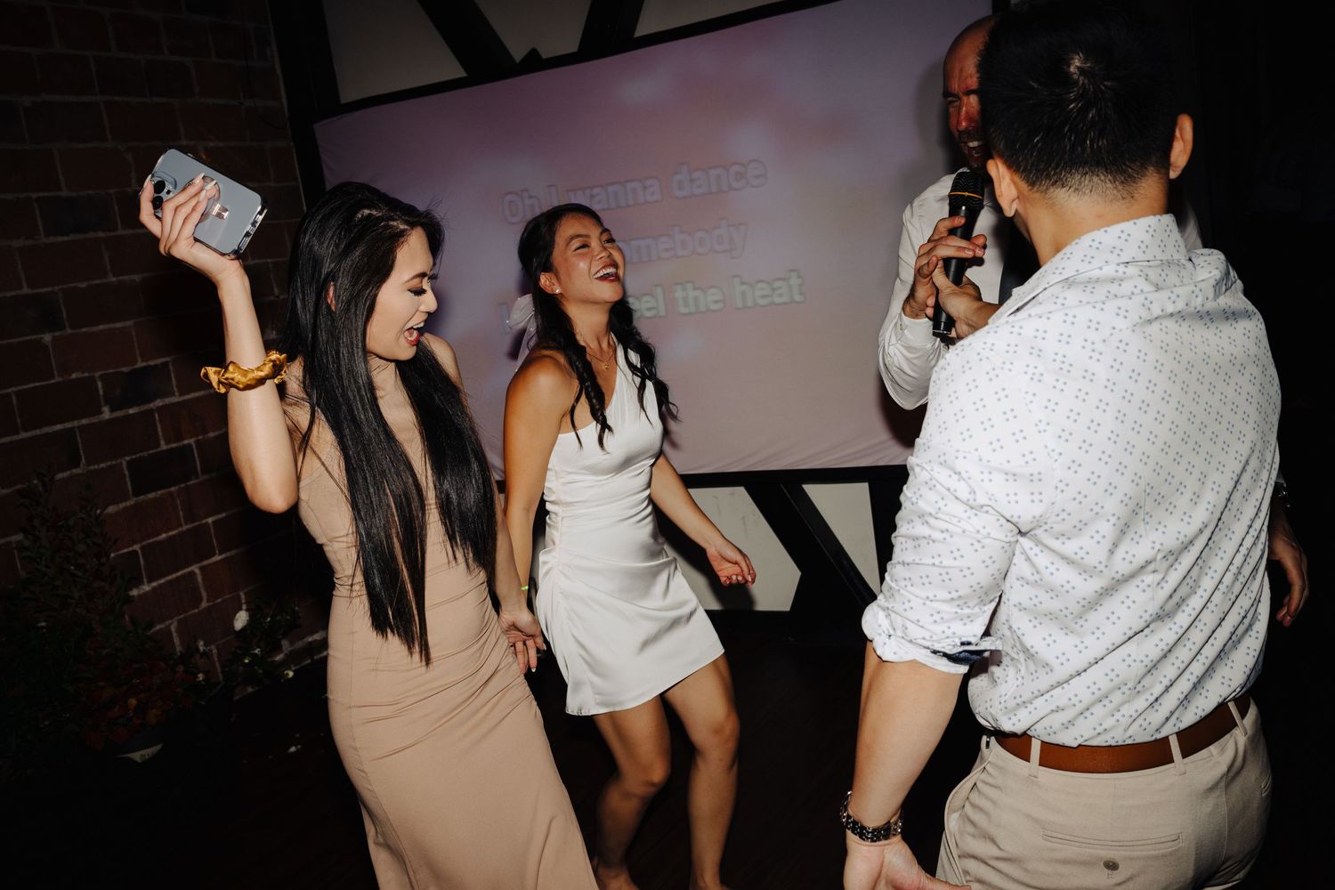 Wedding guests dancing and having fun with drinks at reception party.