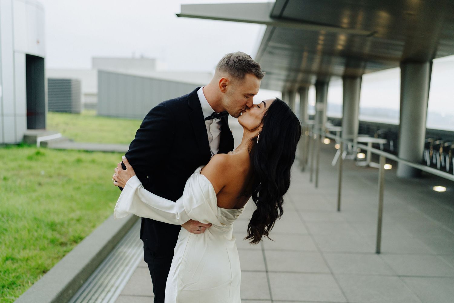 Romantic outdoor wedding portrait of couple embracing under covered walkway.