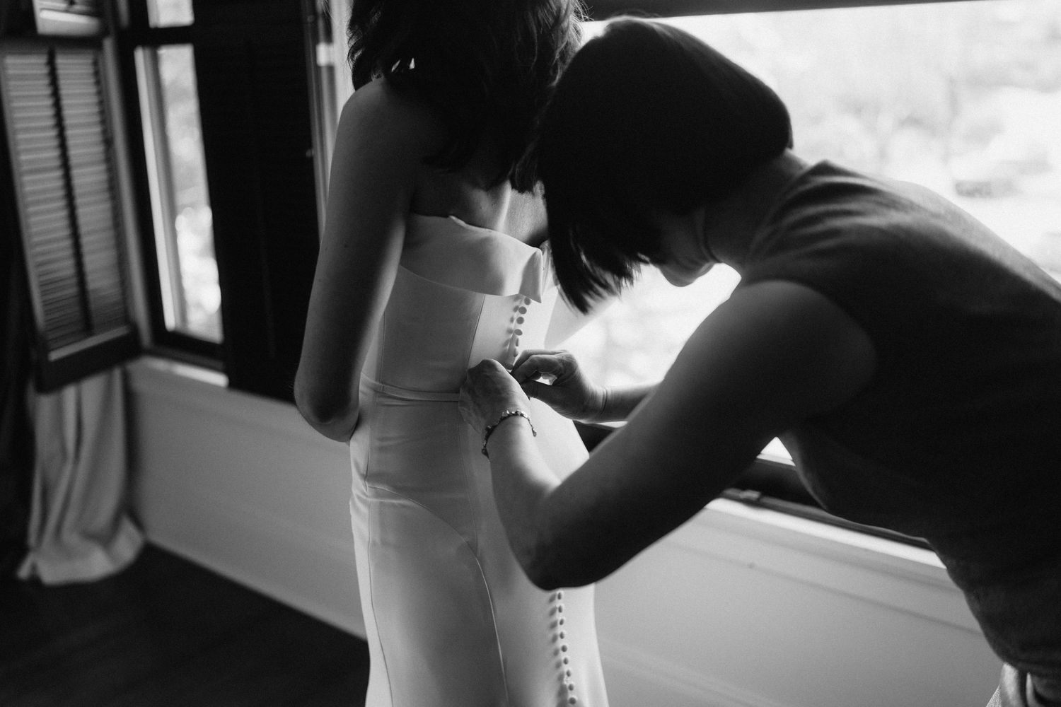 A sequence of black and white candid intimate wedding photos showing a couple sharing private moments near a window.