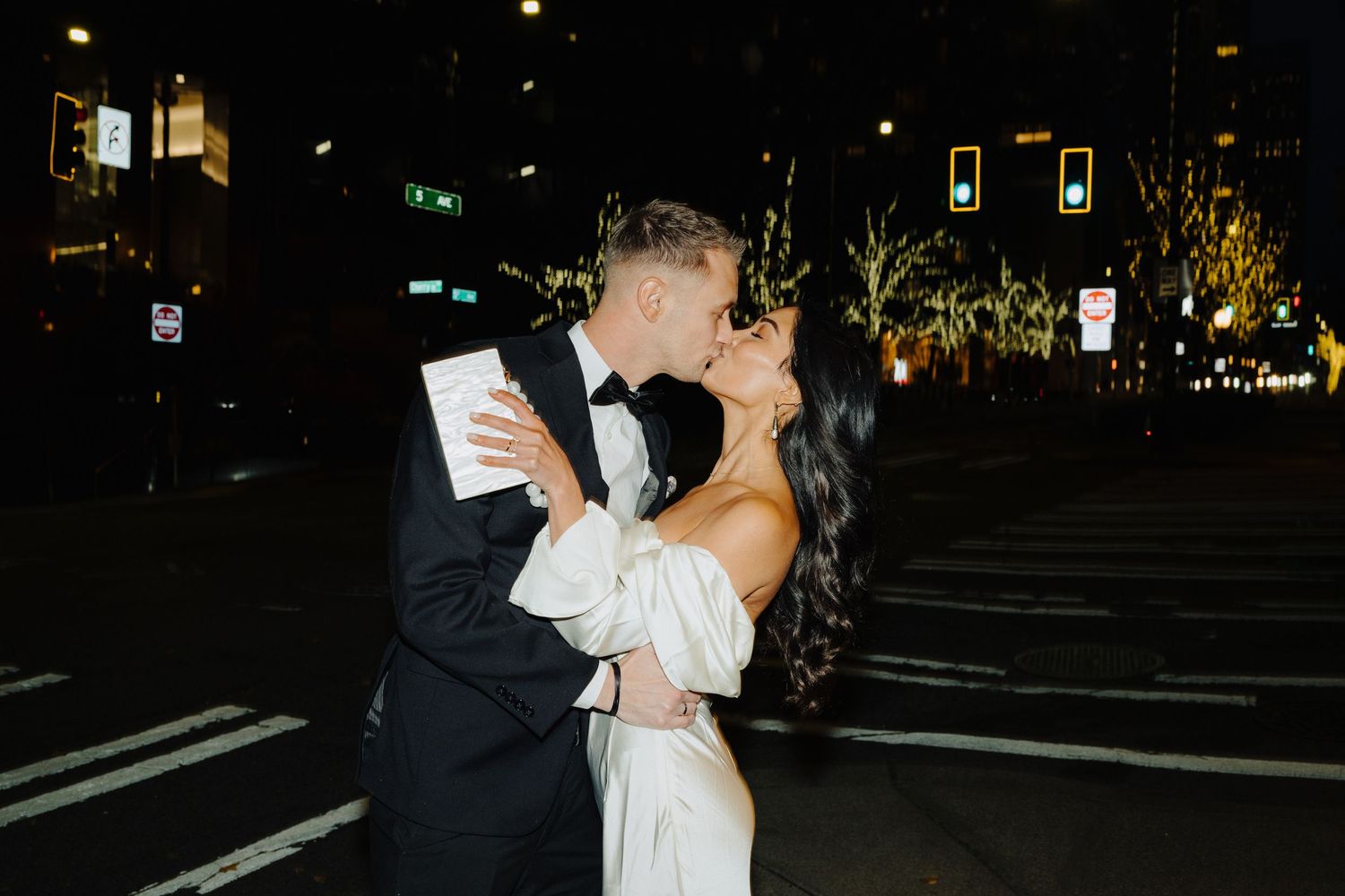 Nighttime wedding portrait with city lights and street signs in the background.