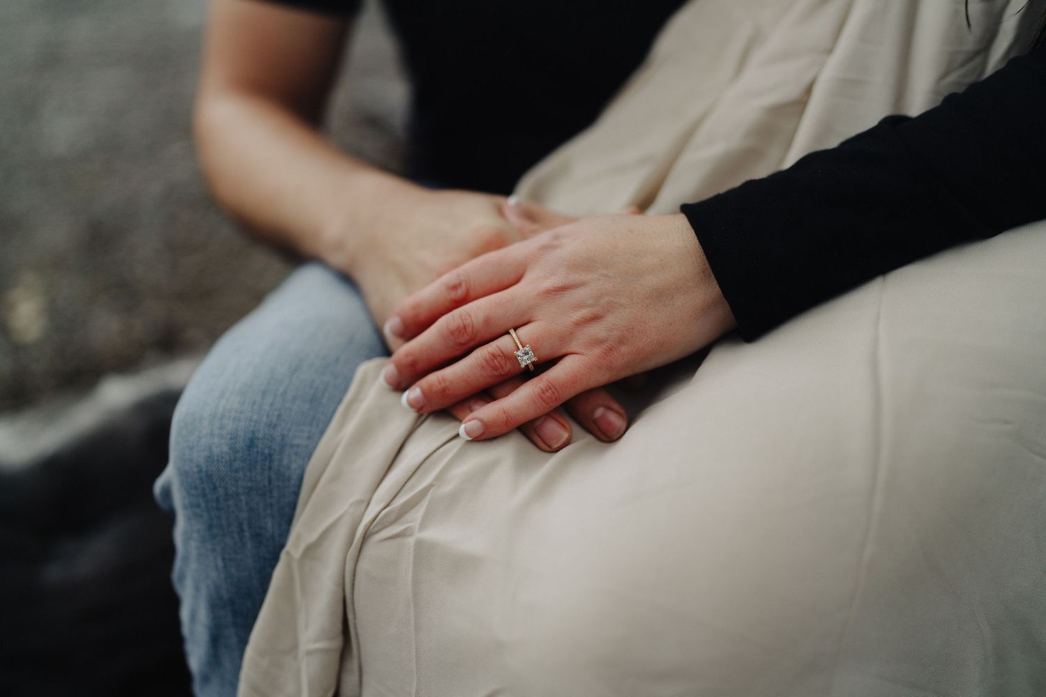 Close-up view of two hands gently touching on a fabric surface while sitting on a stone step.