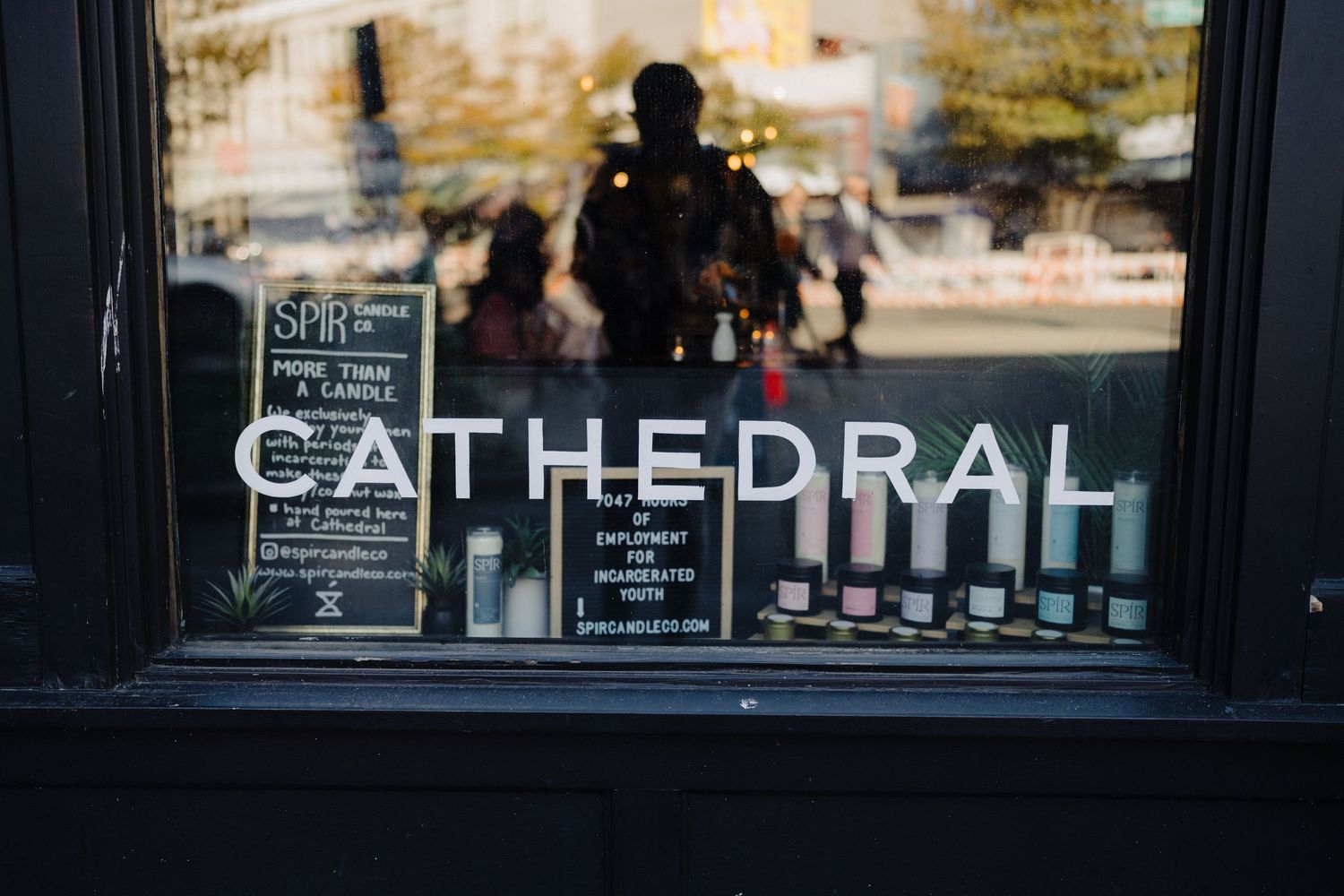 Window display showing 'Cathedral' text with bottles and signage in reflection.