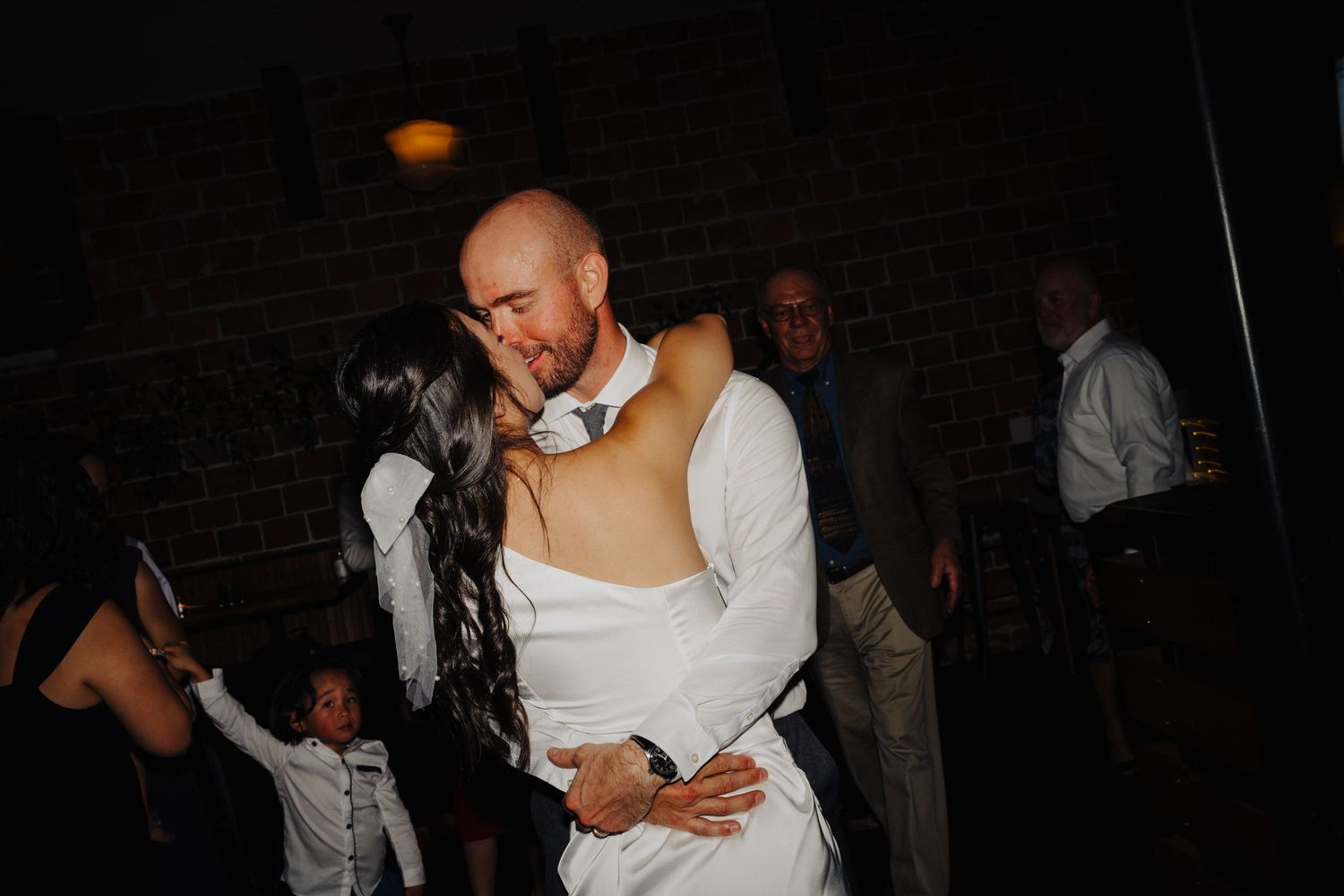 Couples dancing together at a dimly lit wedding reception.
