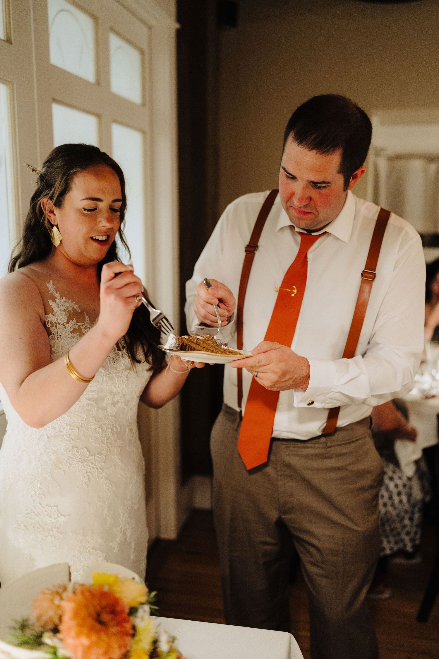 Wedding couple enjoys sharing a plate of food during their reception.