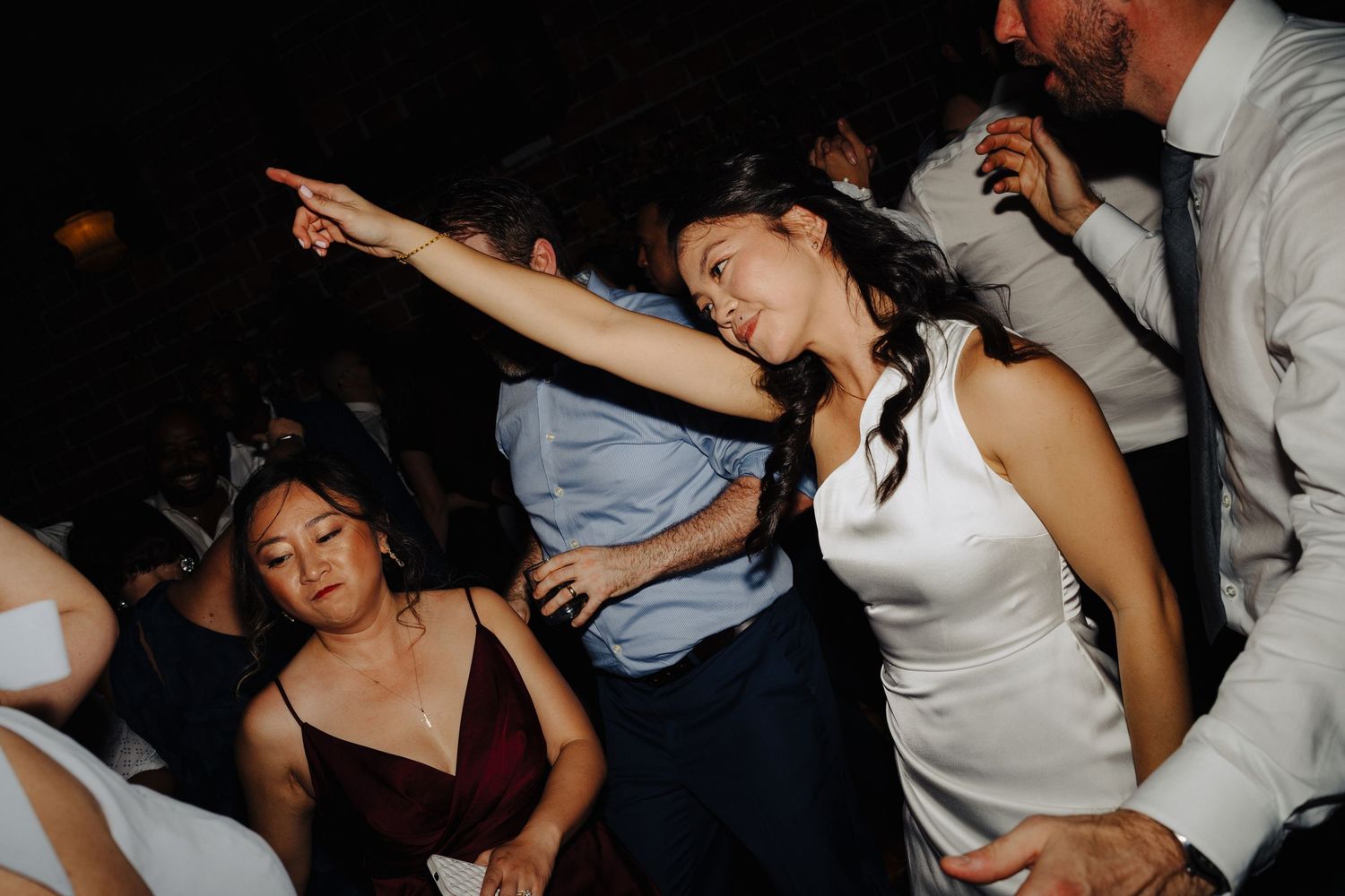 Wedding guests dancing enthusiastically on a crowded dance floor.