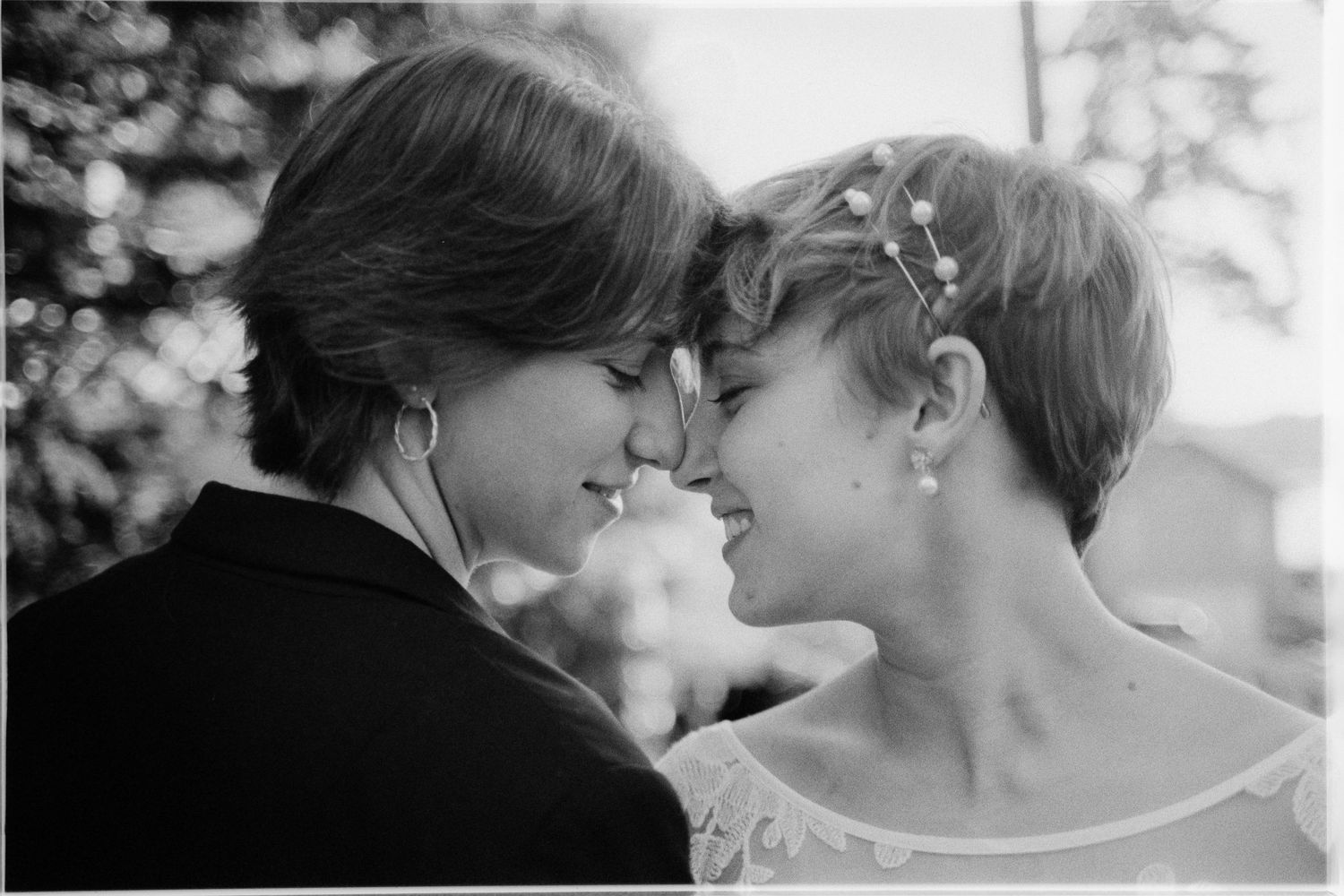 A romantic black and white photograph showing two people touching noses in an intimate moment outdoors.