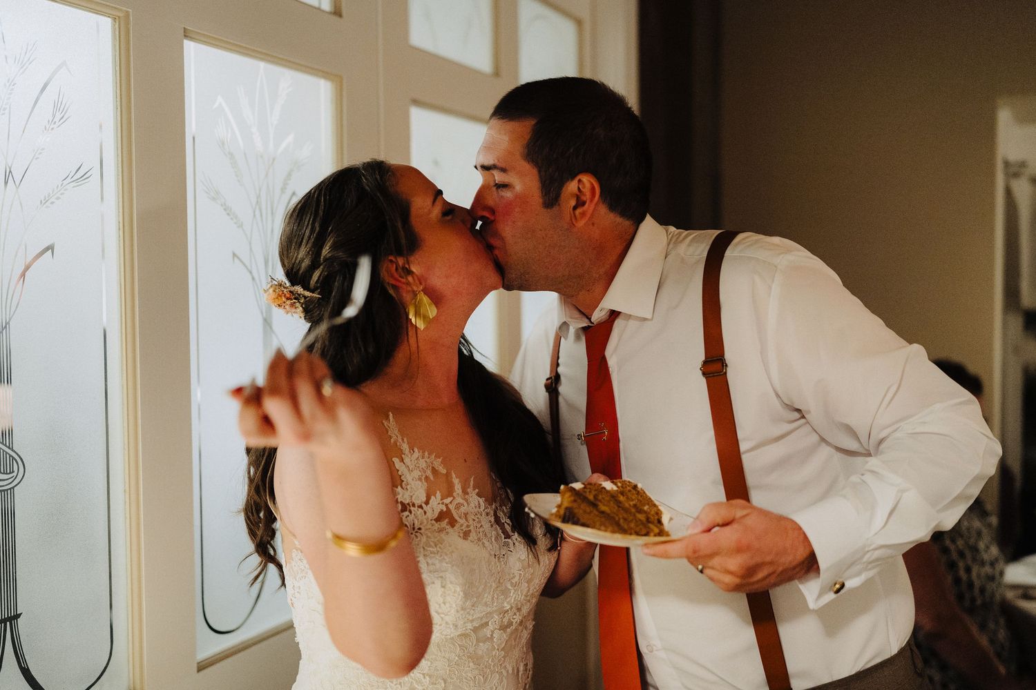 A newlywed couple shares a playful moment while eating cake at their wedding reception.