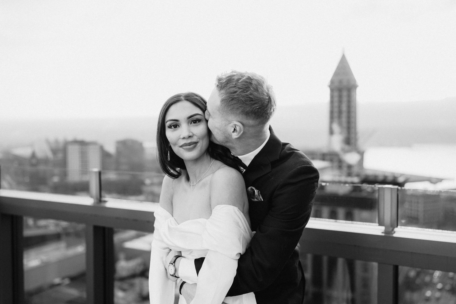 Black and white portrait of romantic couple sharing intimate moment on city rooftop.