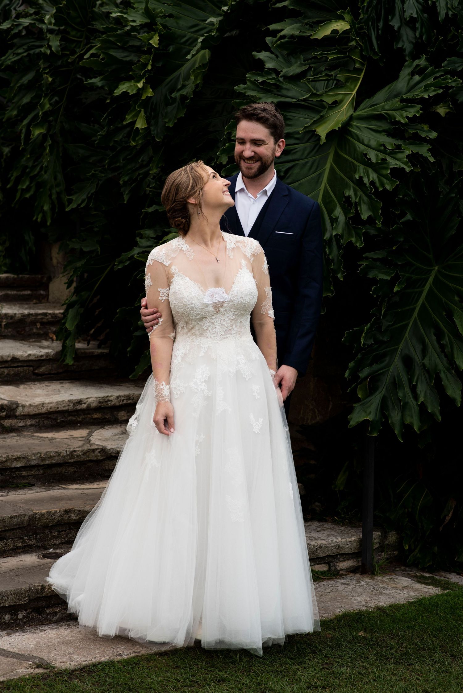 Bride and groom share a joyful moment on the lush stone steps of the Santa Barbara Courthouse during their elegant wedding.