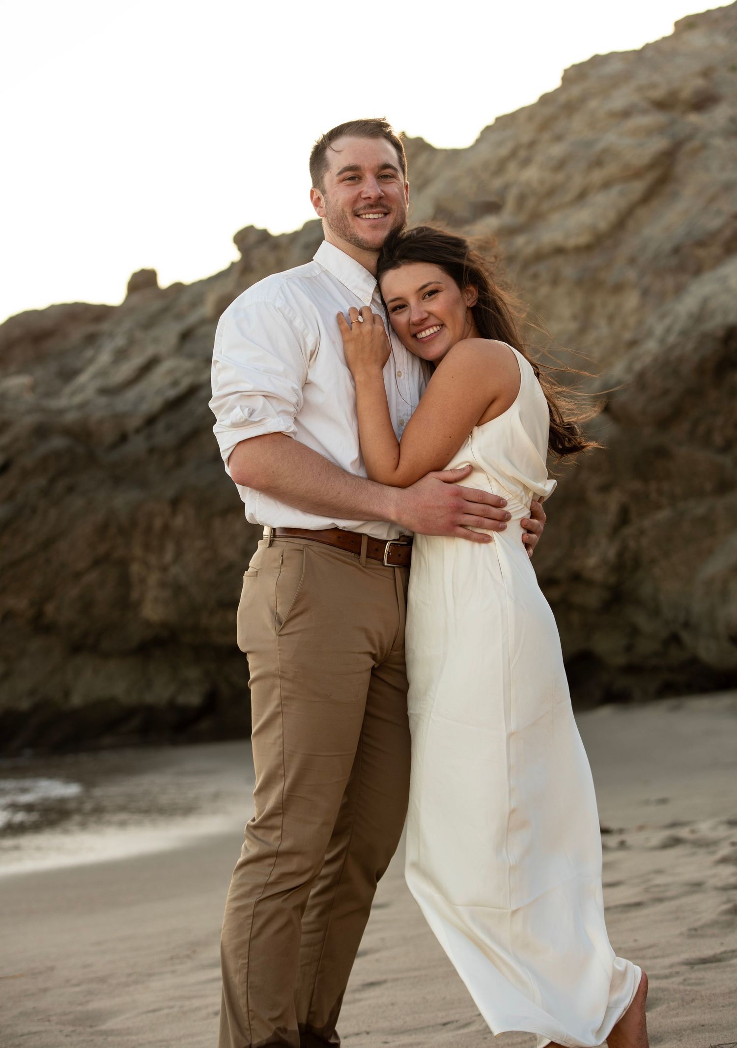Engaged couple posing on a beach at sunset in Malibu, California during their romantic coastal engagement photo session.