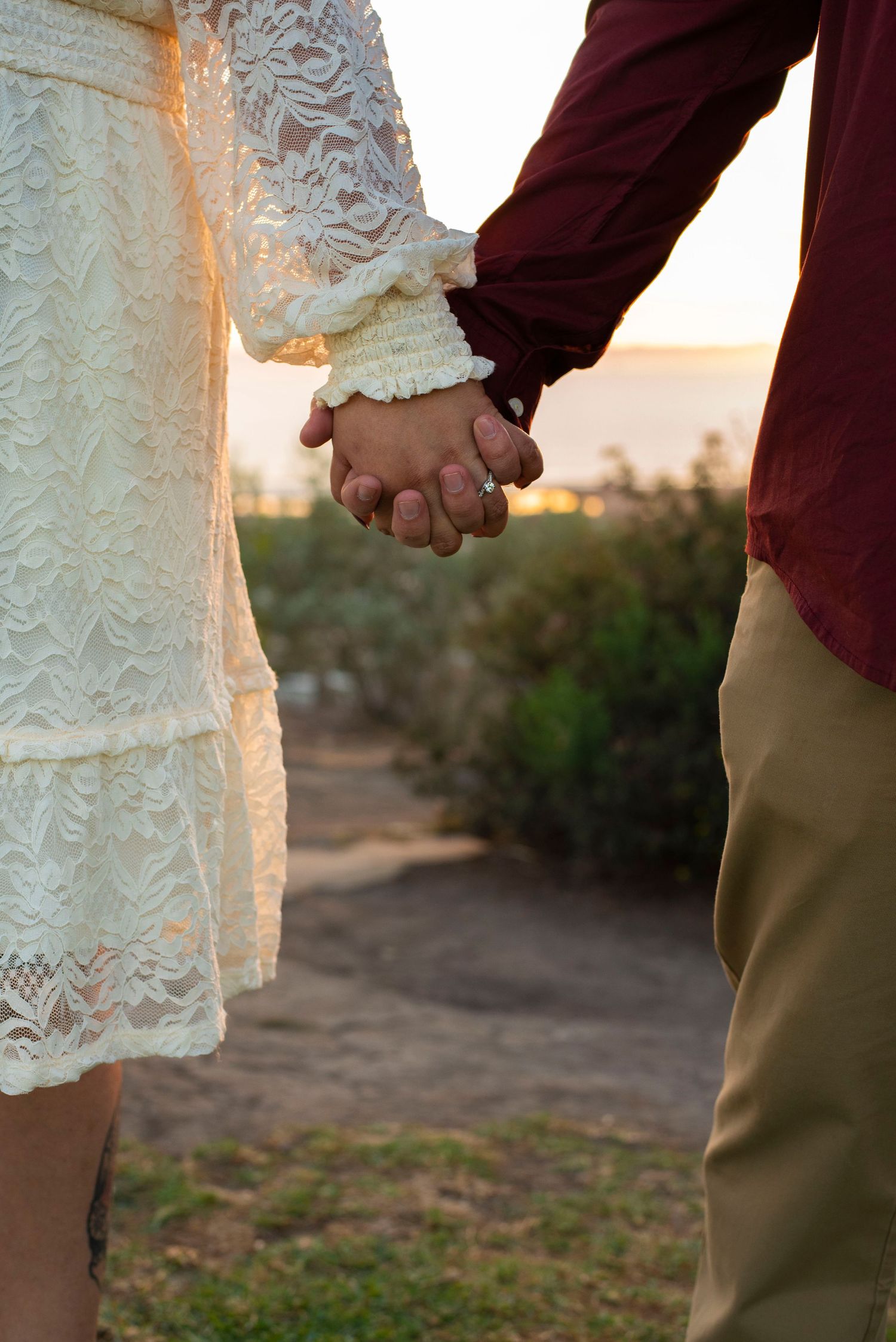 Close-up of a couple holding hands during a golden hour engagement shoot at Grant Park in Ventura, CA.