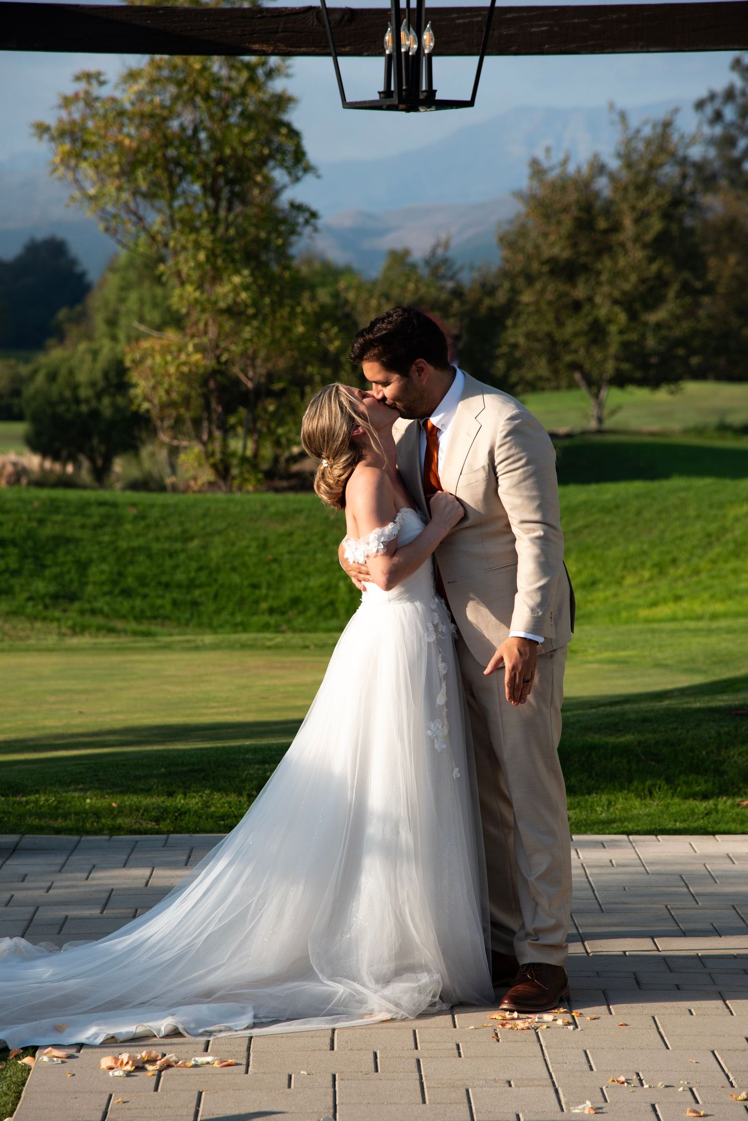 Bride and groom kissing at a romantic outdoor wedding ceremony at a golf course venue in Camarillo, California, with scenic mountain views.