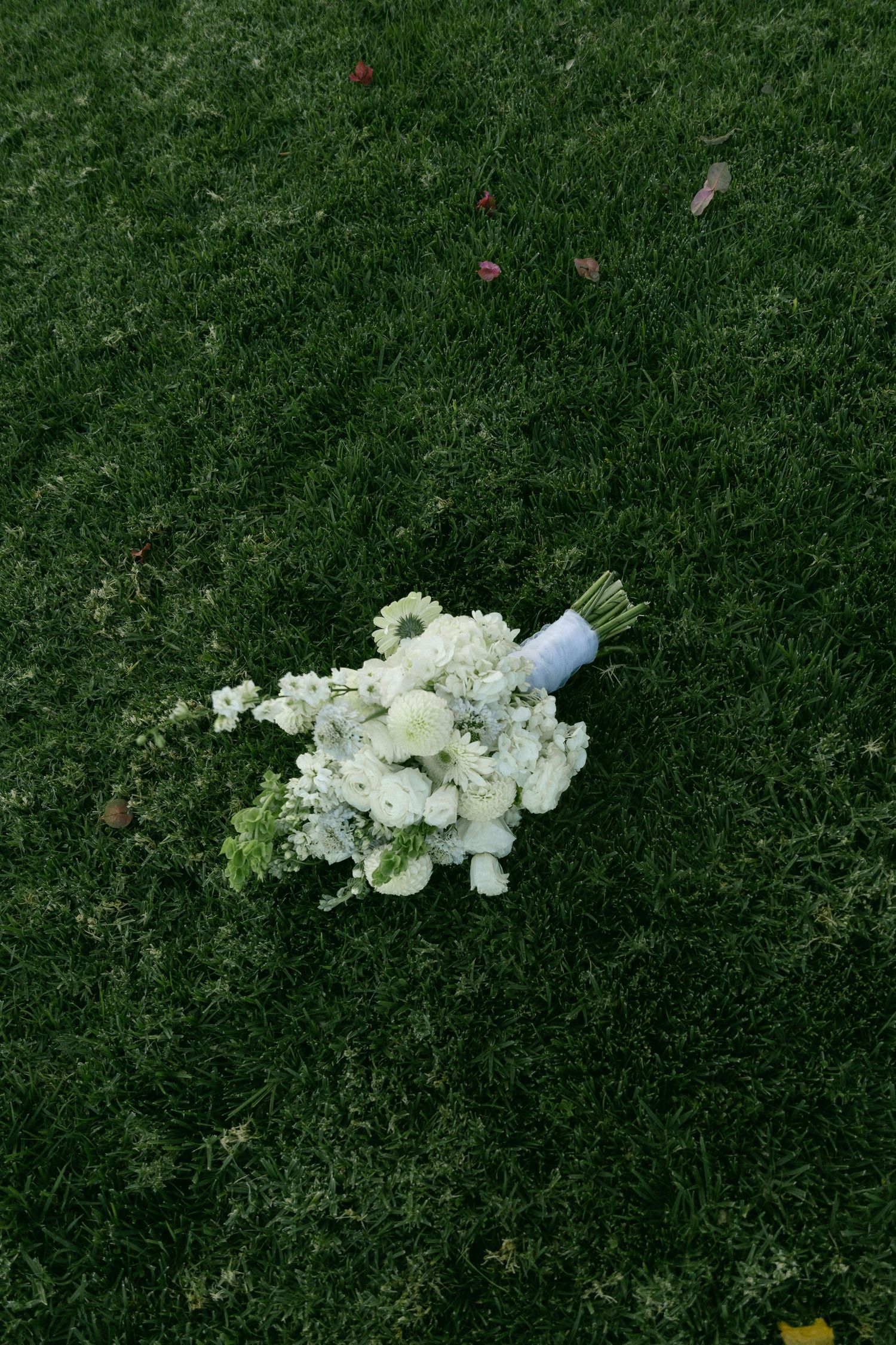 A delicate white floral bouquet rests on vibrant green grass. Documentary photographer
