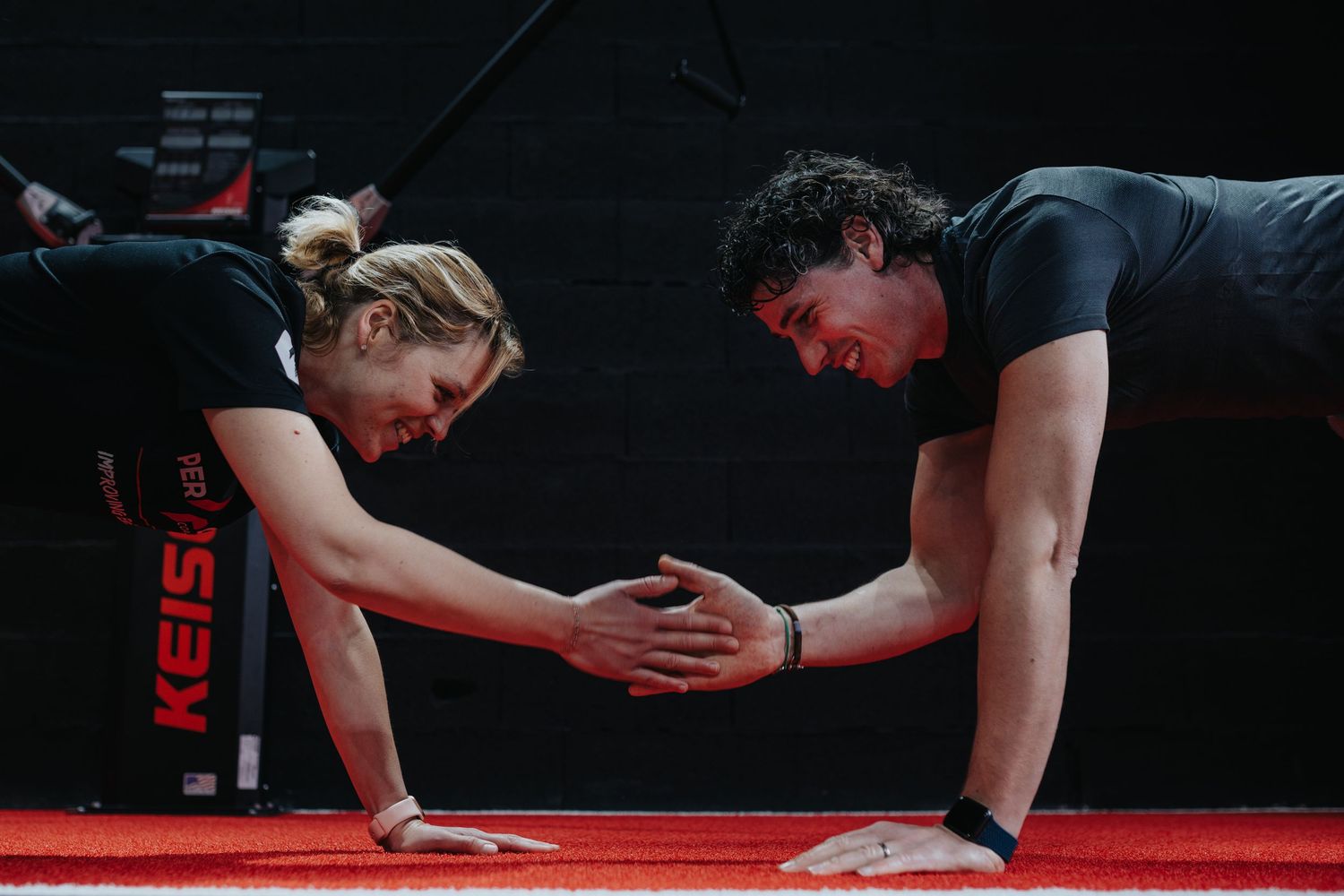 Athletes perform backbends in synchronized positions during a gymnastics competition on red mats.