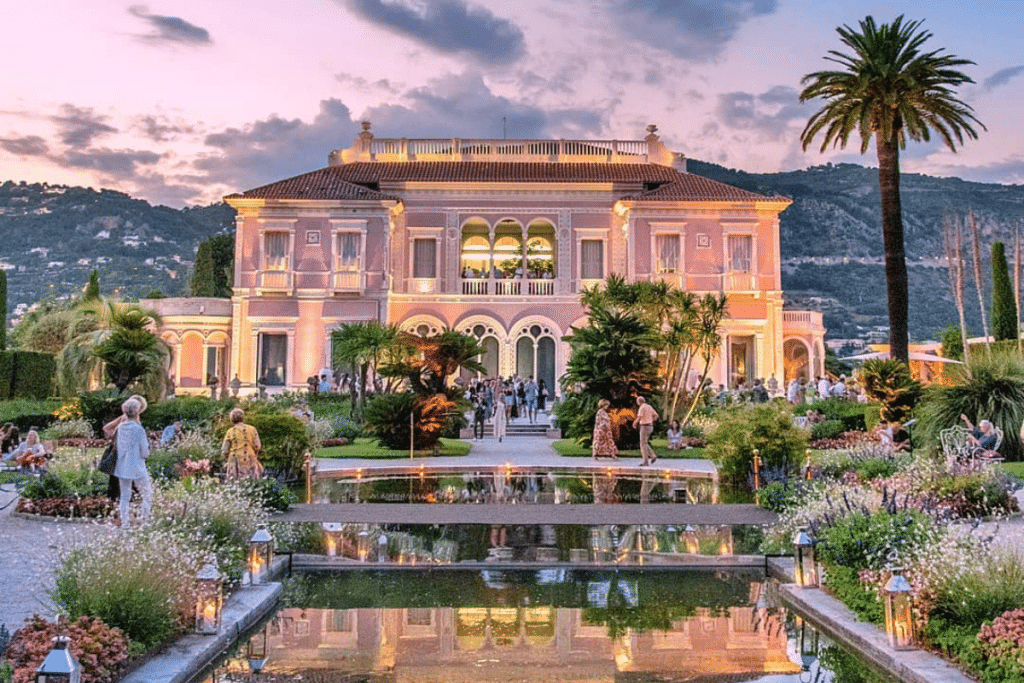 Luxurious pink Villa Ephrussi de Rothschild mansion in Saint-Jean-Cap-Ferrat with reflecting pool and gardens at sunset.