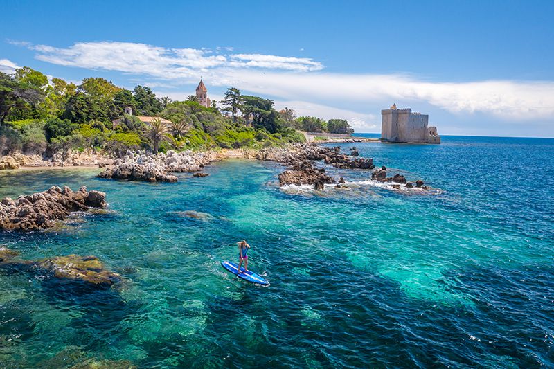 Beautiful turquoise Mediterranean waters and rocky coastline with historic castle near Genoa, Italy on a sunny summer day.
