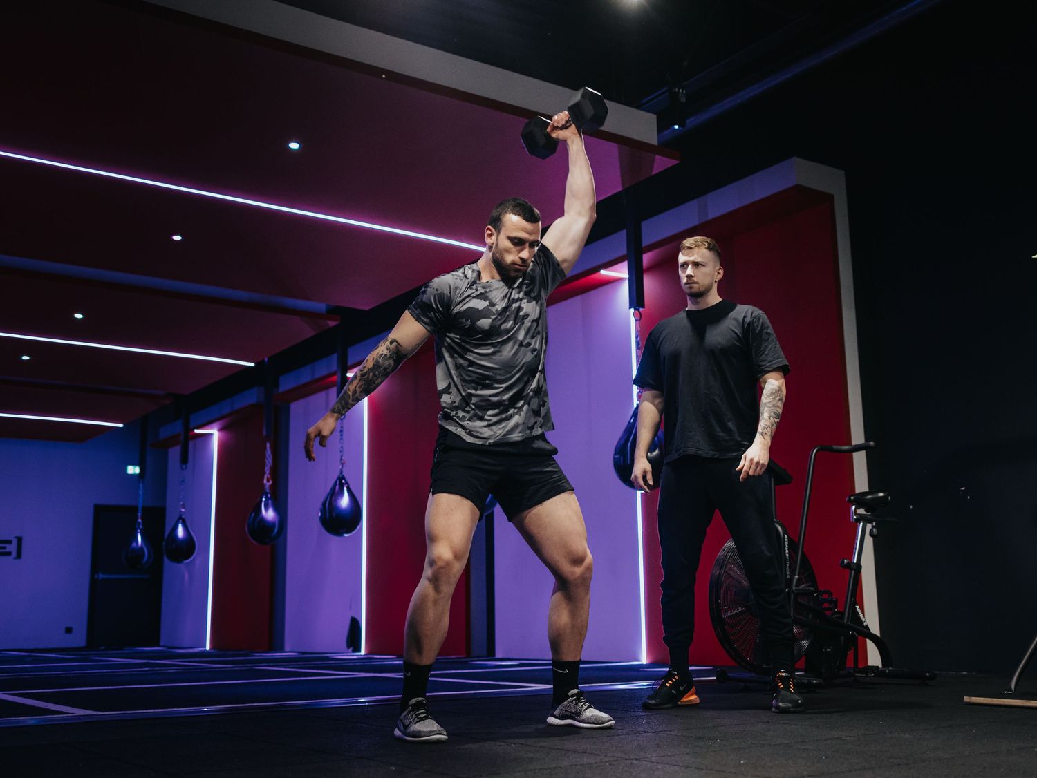 A montage of people exercising in a dark studio with neon lighting shows various workout positions and movements.