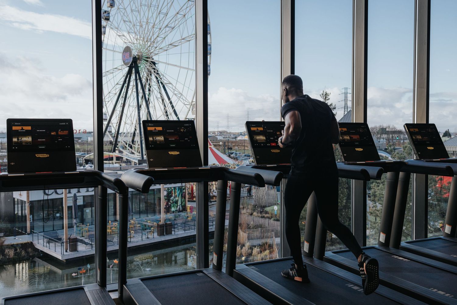 Silhouetted figures overlook Liverpool city from rotating glass viewing deck at sunset.