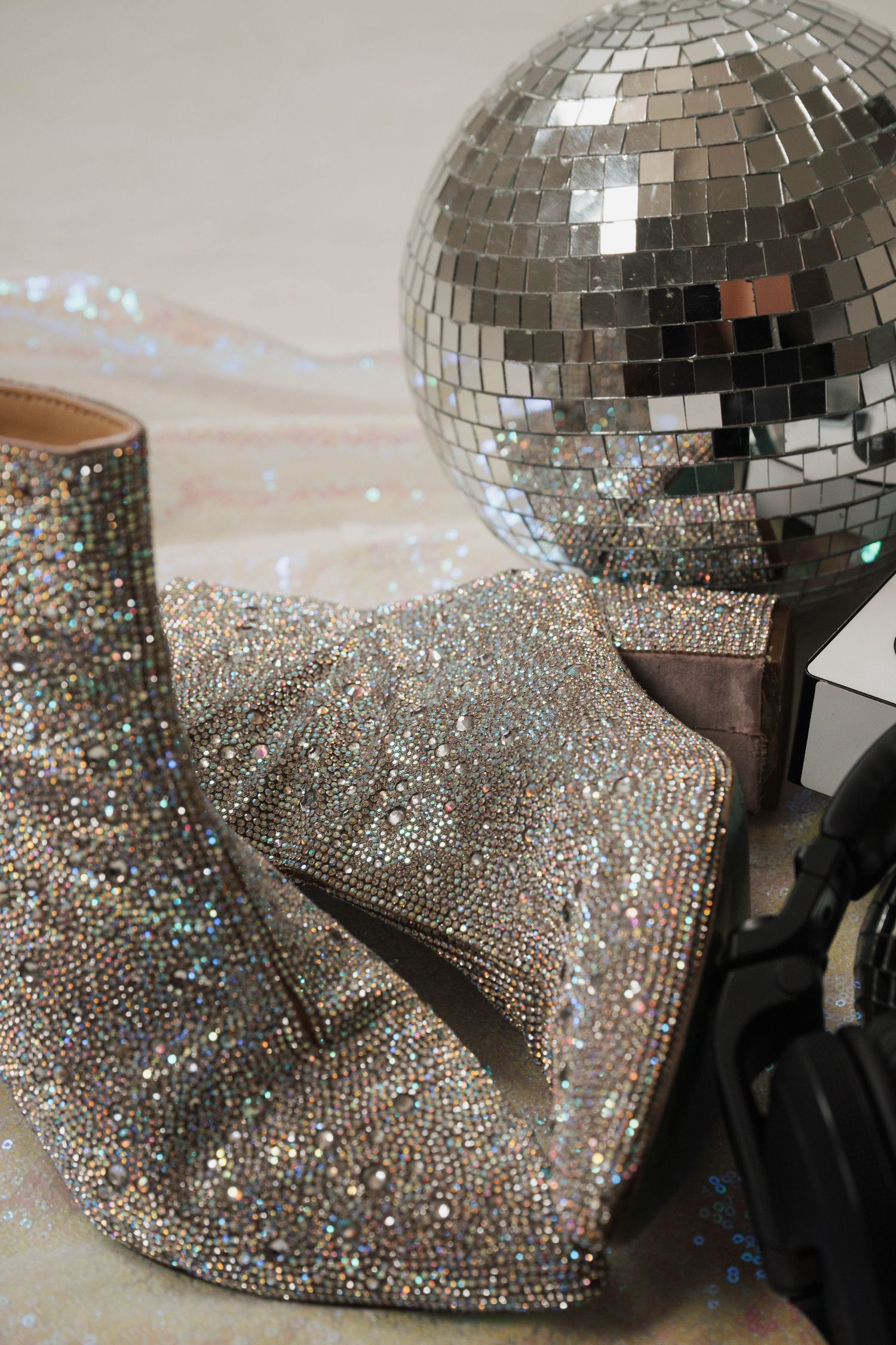 Sparkly silver disco ball next to glittery fabric and sequined material creating a glamorous party scene.