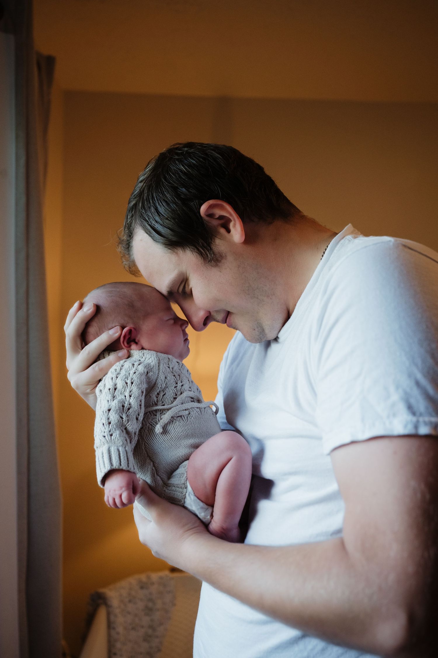 Gentle moment between parent and newborn baby wrapped in knit clothing.
