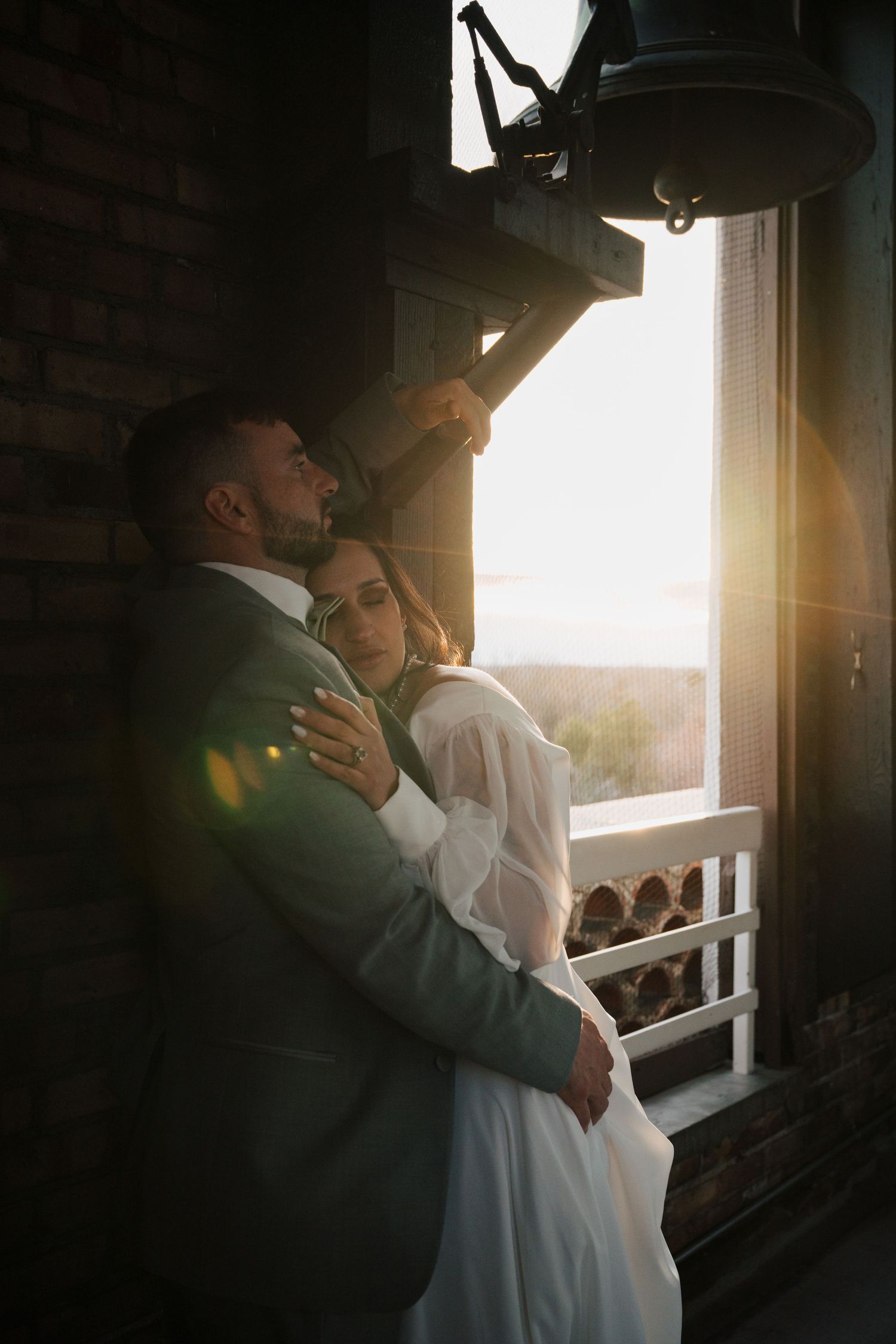 Intimate wedding portrait with sunlight streaming through a window.