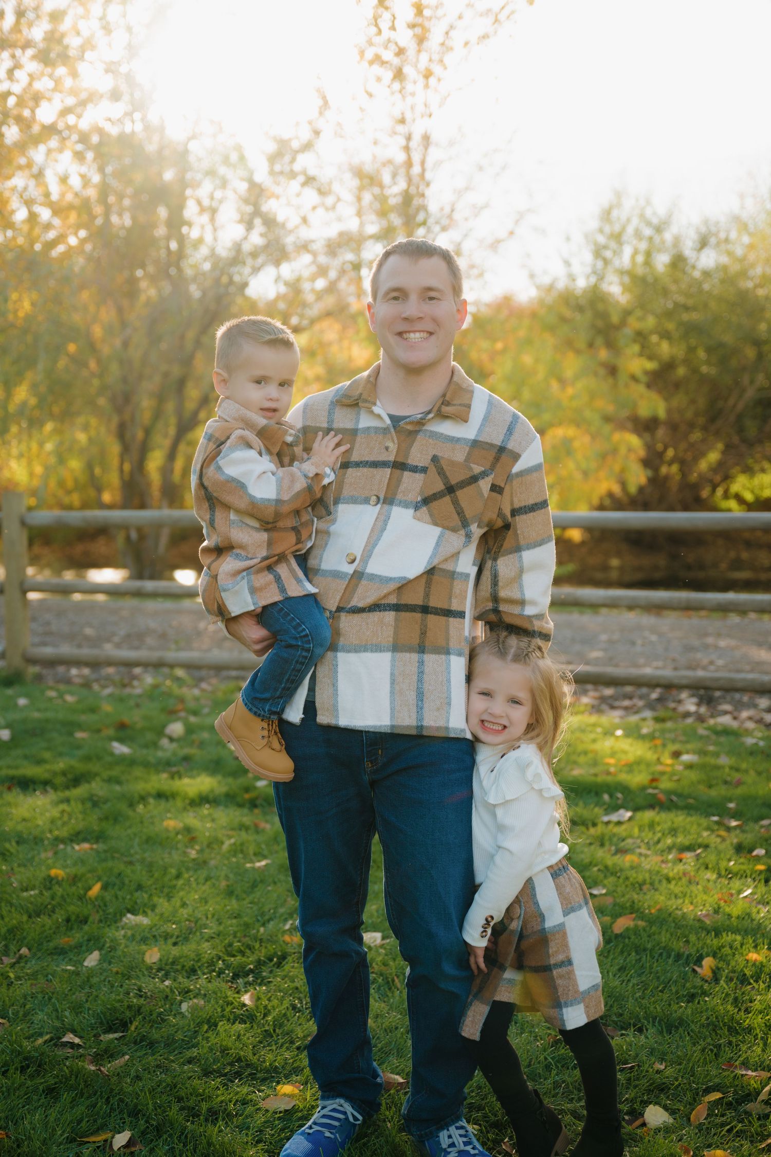 Family portrait in fall setting wearing coordinated plaid flannel shirts and denim against autumn foliage. Star, Idaho Family Photographer