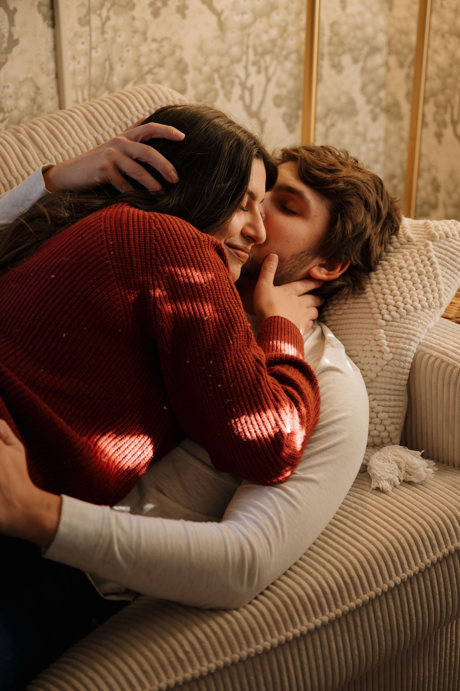 An intimate moment shared between a couple on a comfortable couch in warm lighting.