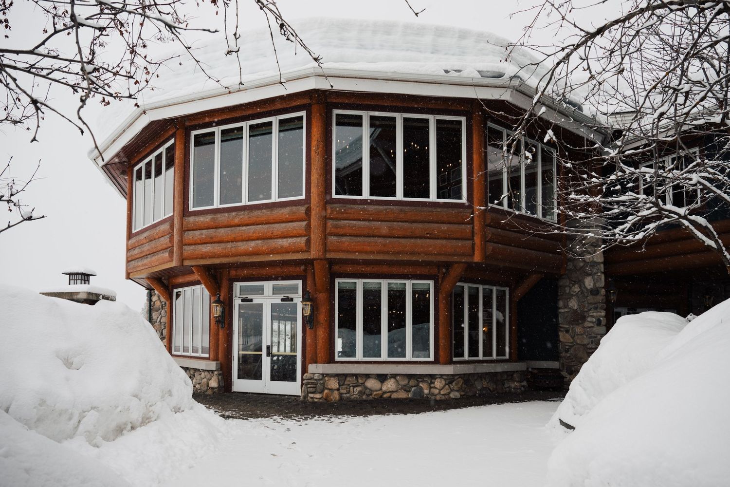 A row of modern wooden cabins with large windows nestled in snowy winter landscape.