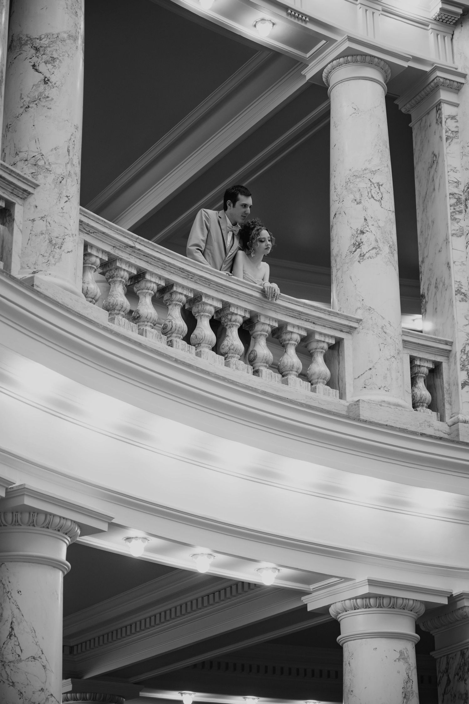 A grand interior view of a historic ballroom with ornate marble columns and balustrades in black and white.