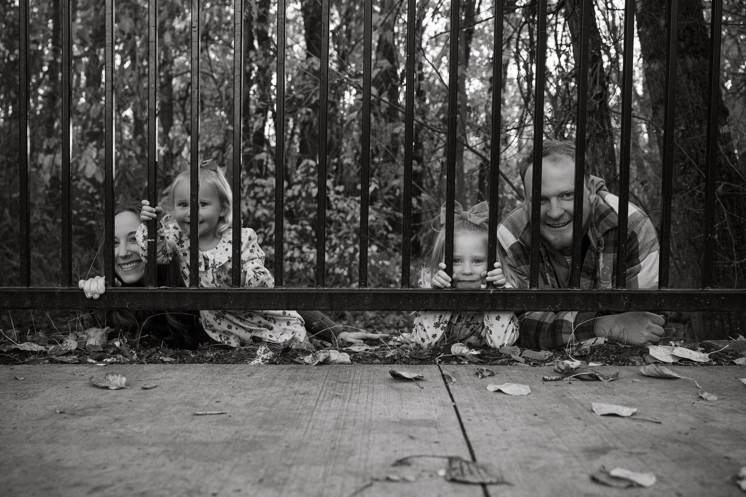 Black and white family photo captured through iron fence bars creating artistic composition.