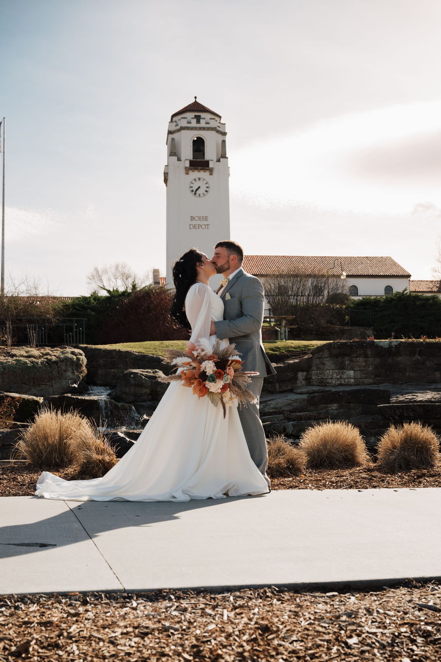 Wedding couple kissing in front of Spanish-style bell tower and mission building.