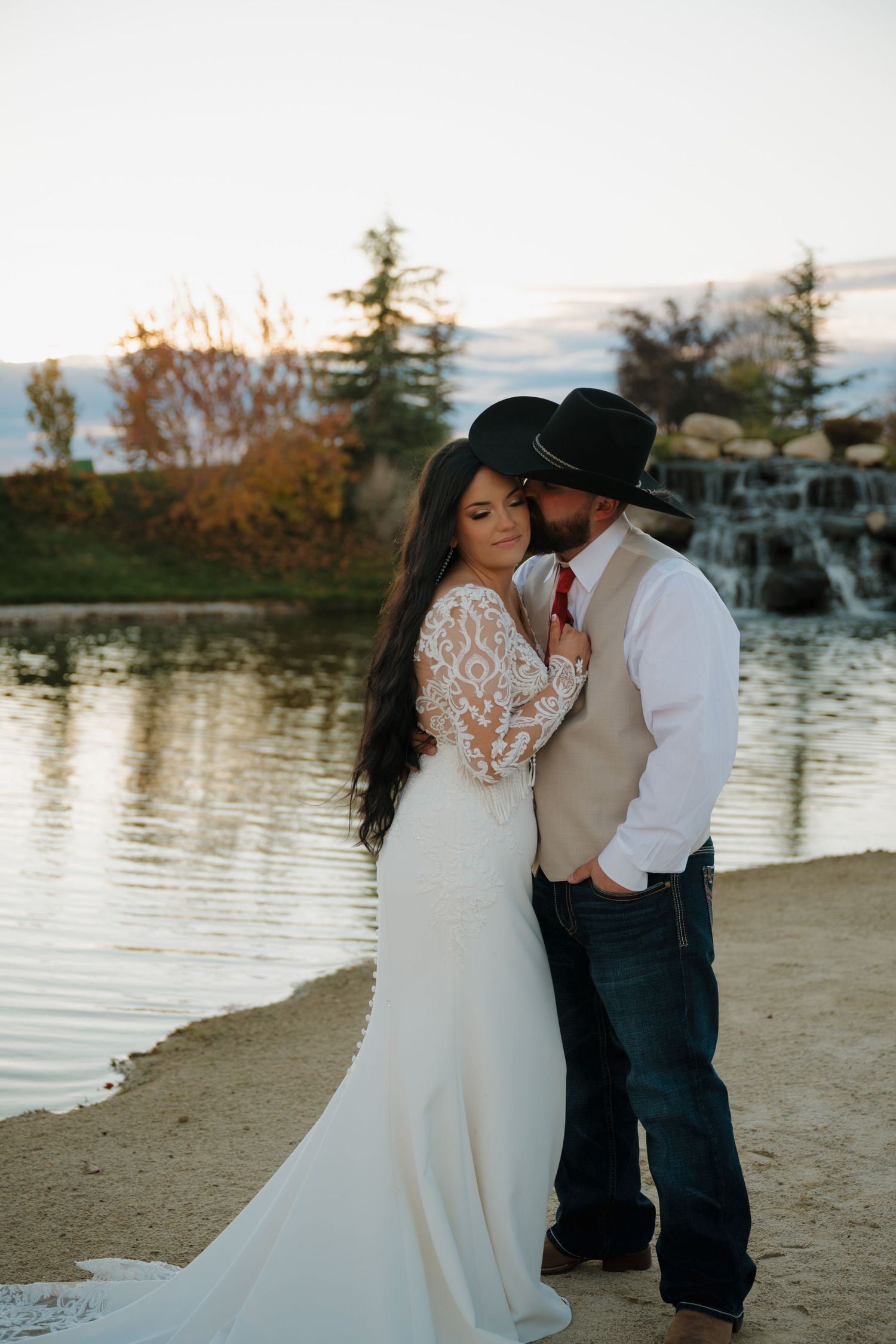 A romantic wedding photo by a lake at sunset with rustic western style.