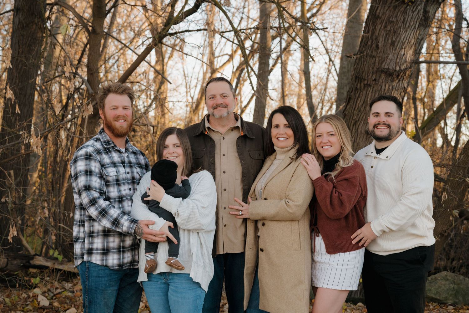 A casual outdoor family portrait in the woods during autumn.
