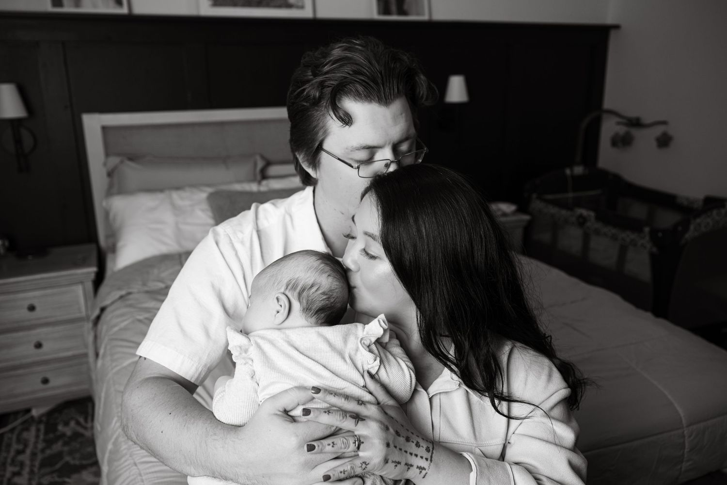 A tender family moment as parents bond with their newborn baby in a dimly lit bedroom.