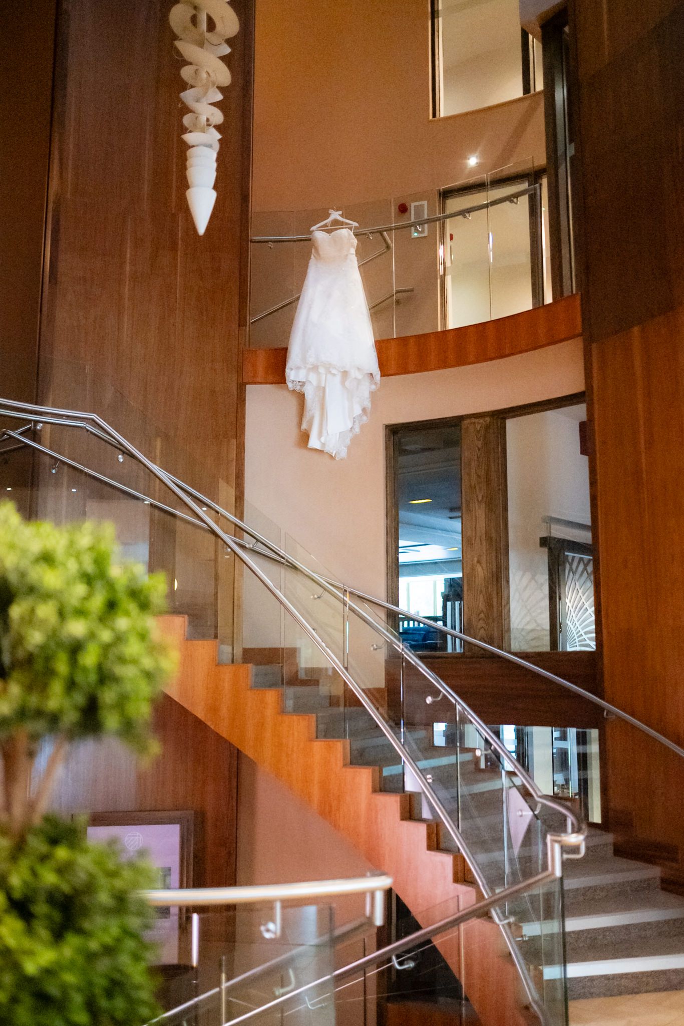 Modern staircase with glass railings and wood paneled walls illuminated by pendant lights in contemporary interior design.