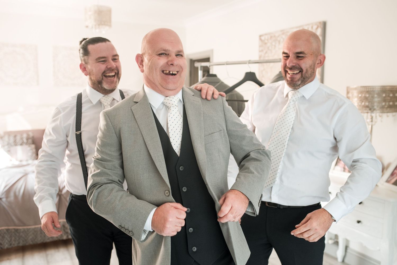 Three people in formal attire share a lighthearted moment together while getting ready.