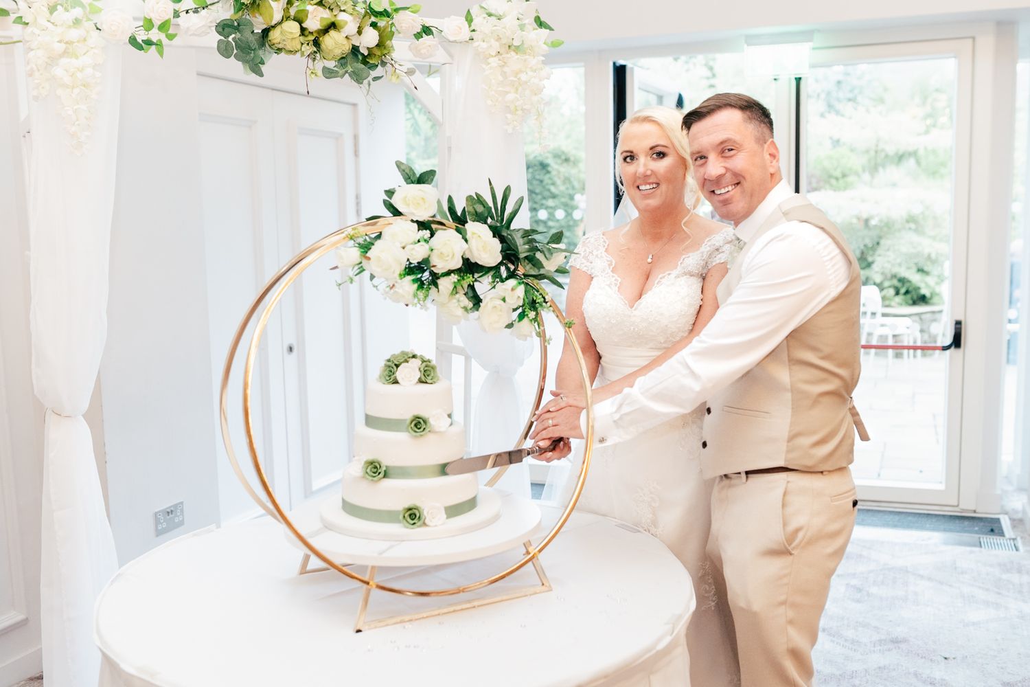 A couple cuts their modern circular-framed white wedding cake together during their reception celebration.