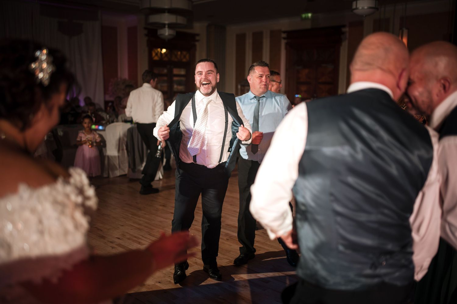 Wedding reception guests dance and celebrate on a dimly lit dance floor during an evening celebration.
