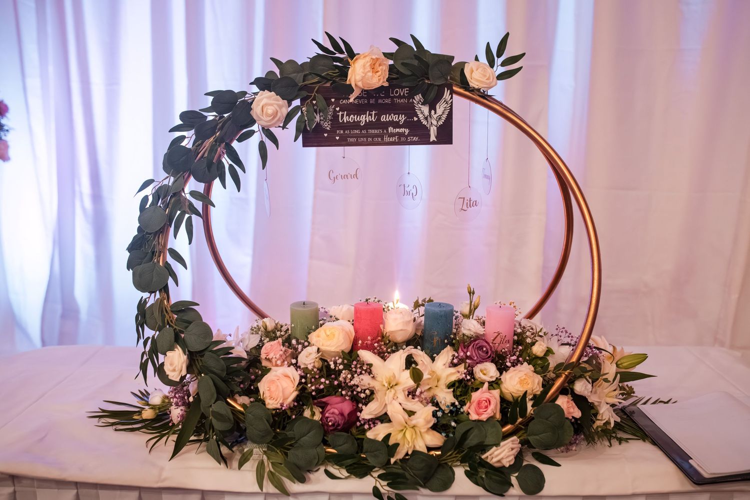 Elegant centerpiece arrangements featuring fresh flowers and greenery adorn a white tablecloth-covered table at a formal event.