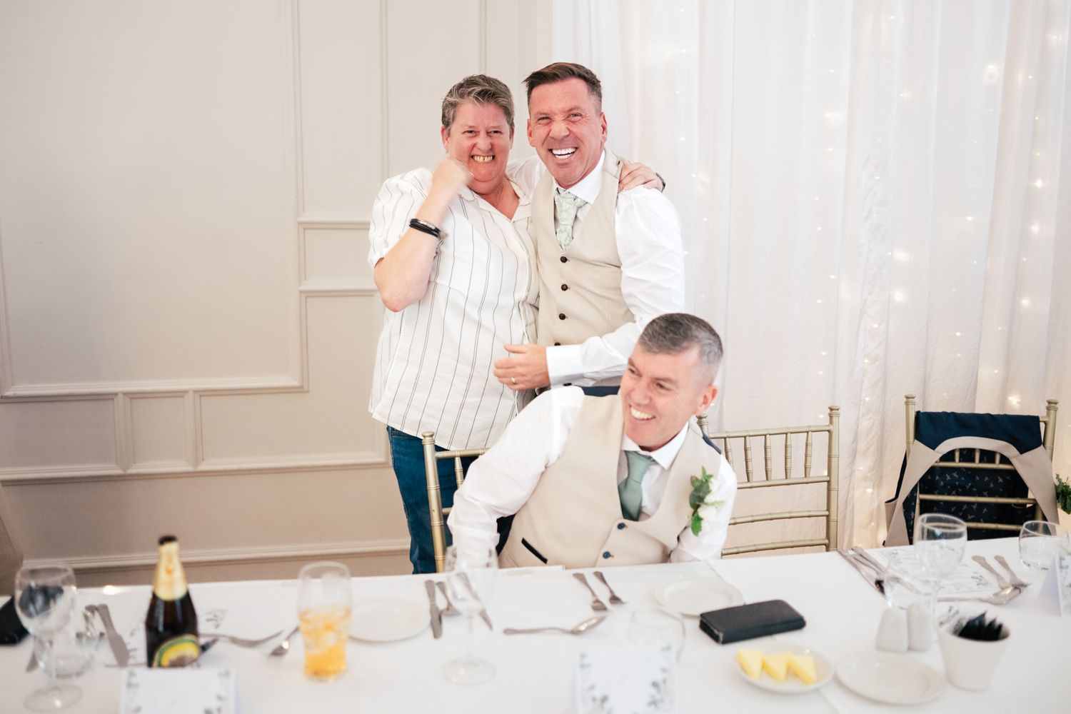 Wedding guests sharing a joyful moment during a celebration at an elegant white reception venue.