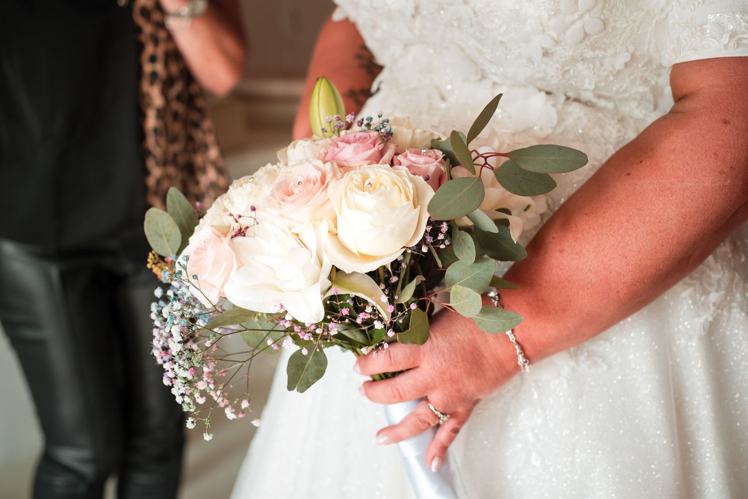 Bridal bouquet details showing delicate white roses and green eucalyptus leaves.