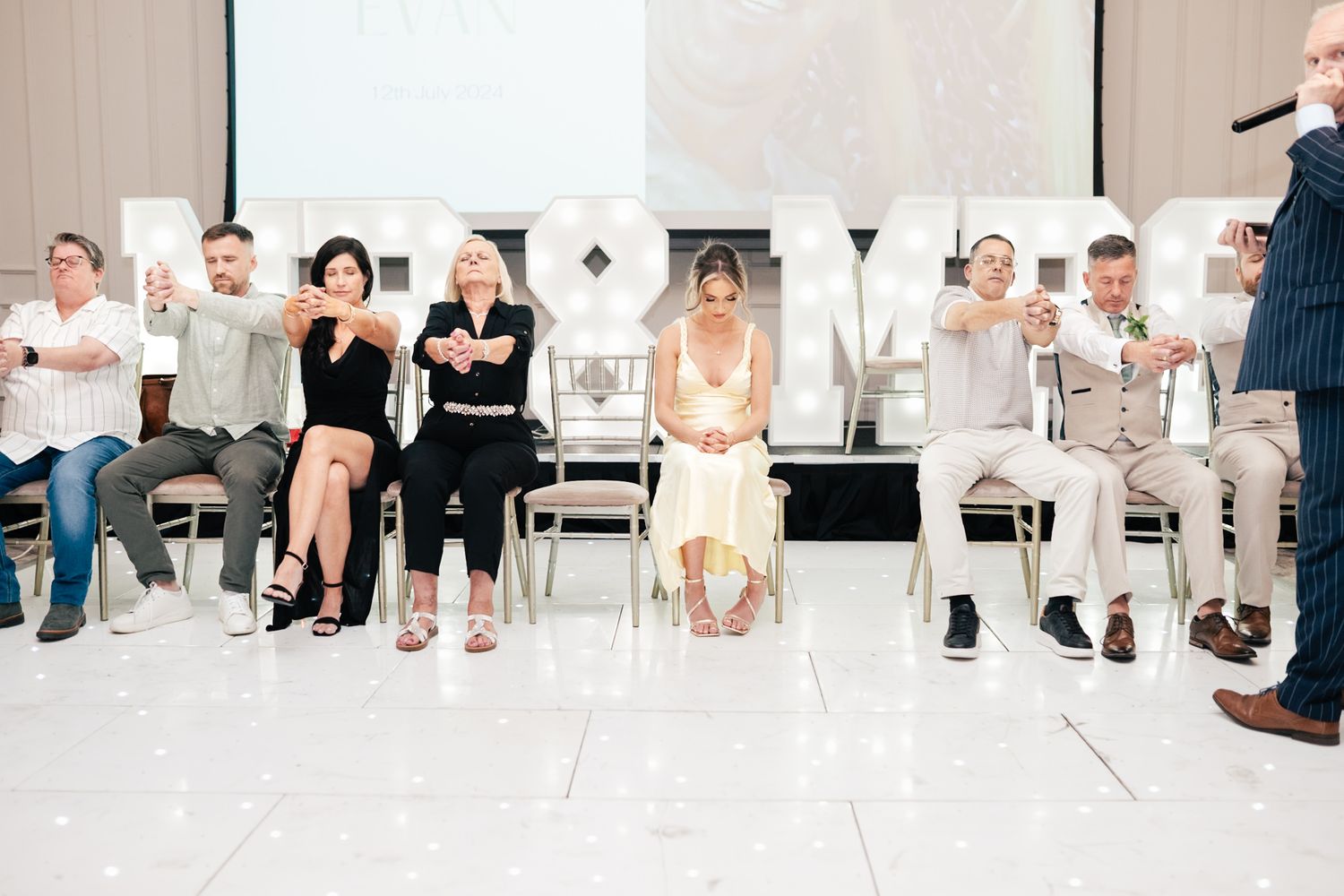 A panoramic view of people's feet and lower legs forming a line against a white background.