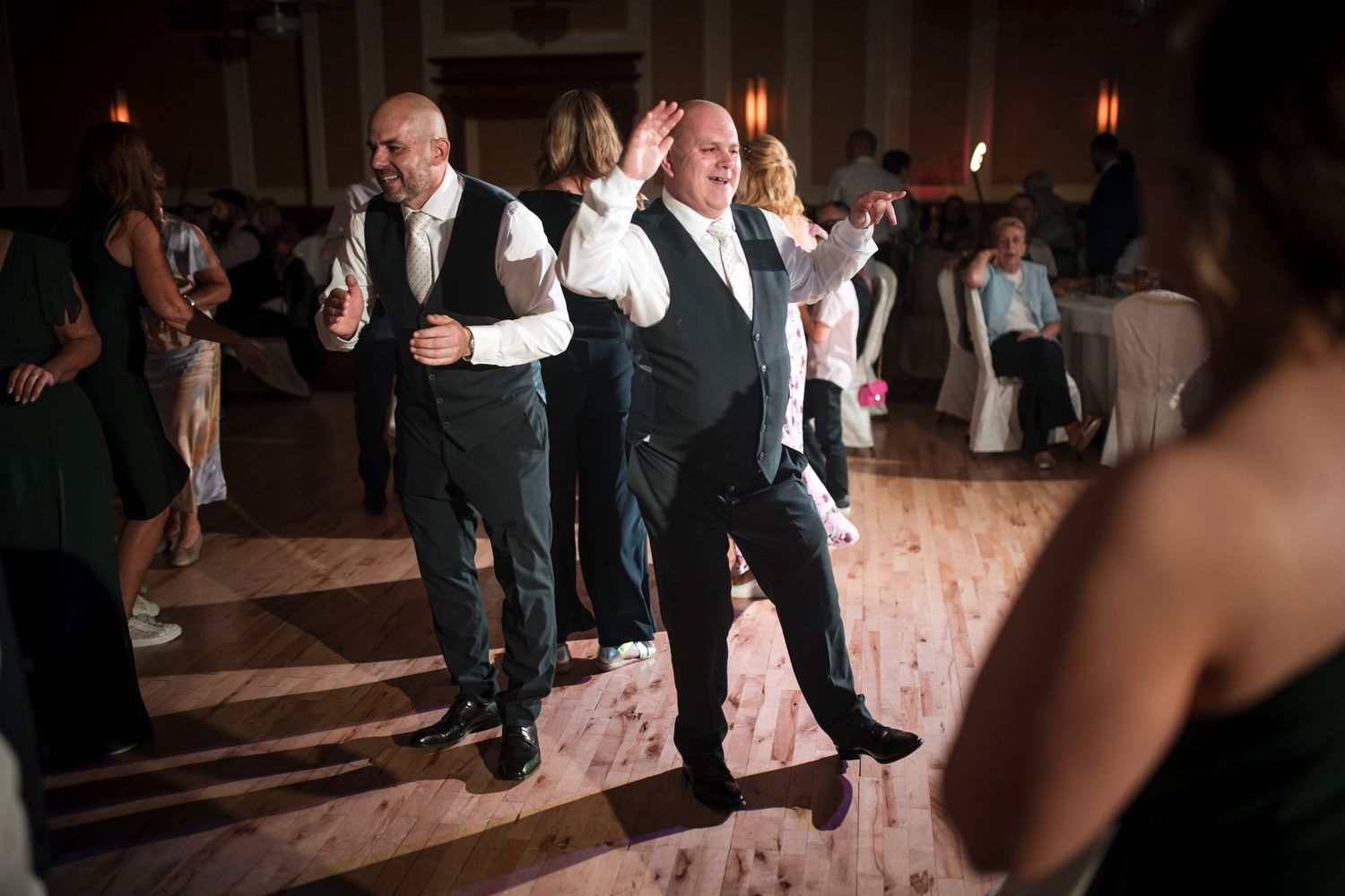 Groomsmen perform a choreographed dance routine at a wedding reception on the dance floor.