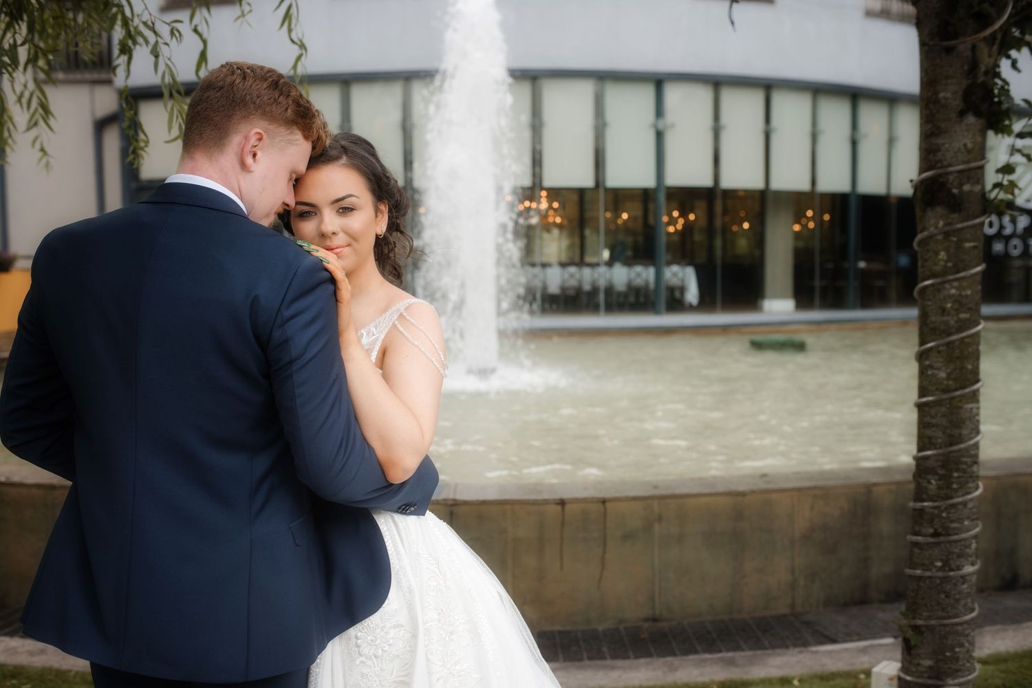 A tender moment between newlyweds next to a fountain.