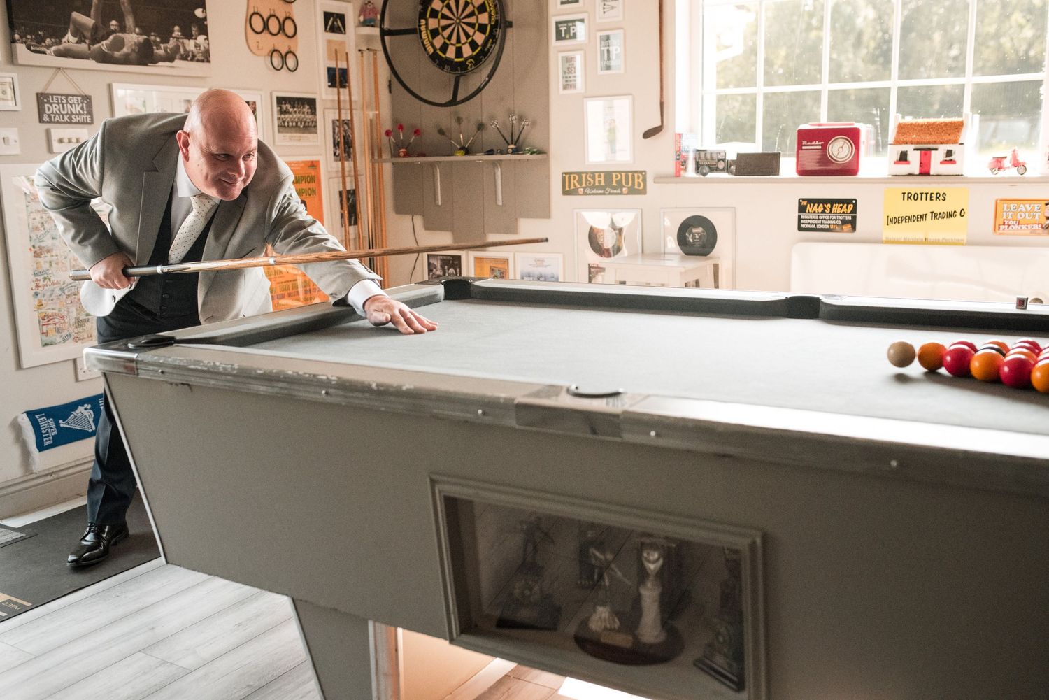 A close-up view of a billiards pool table with vintage decor and memorabilia on the wall in the background.