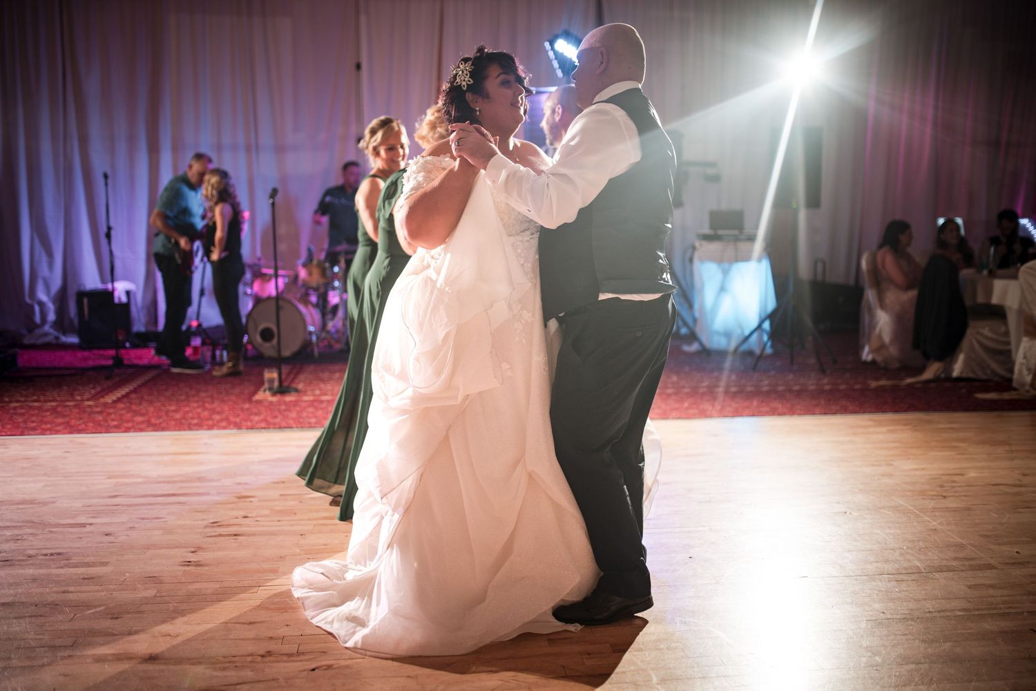 Couple dancing on a lit dance floor during their first dance at a wedding reception with purple mood lighting.