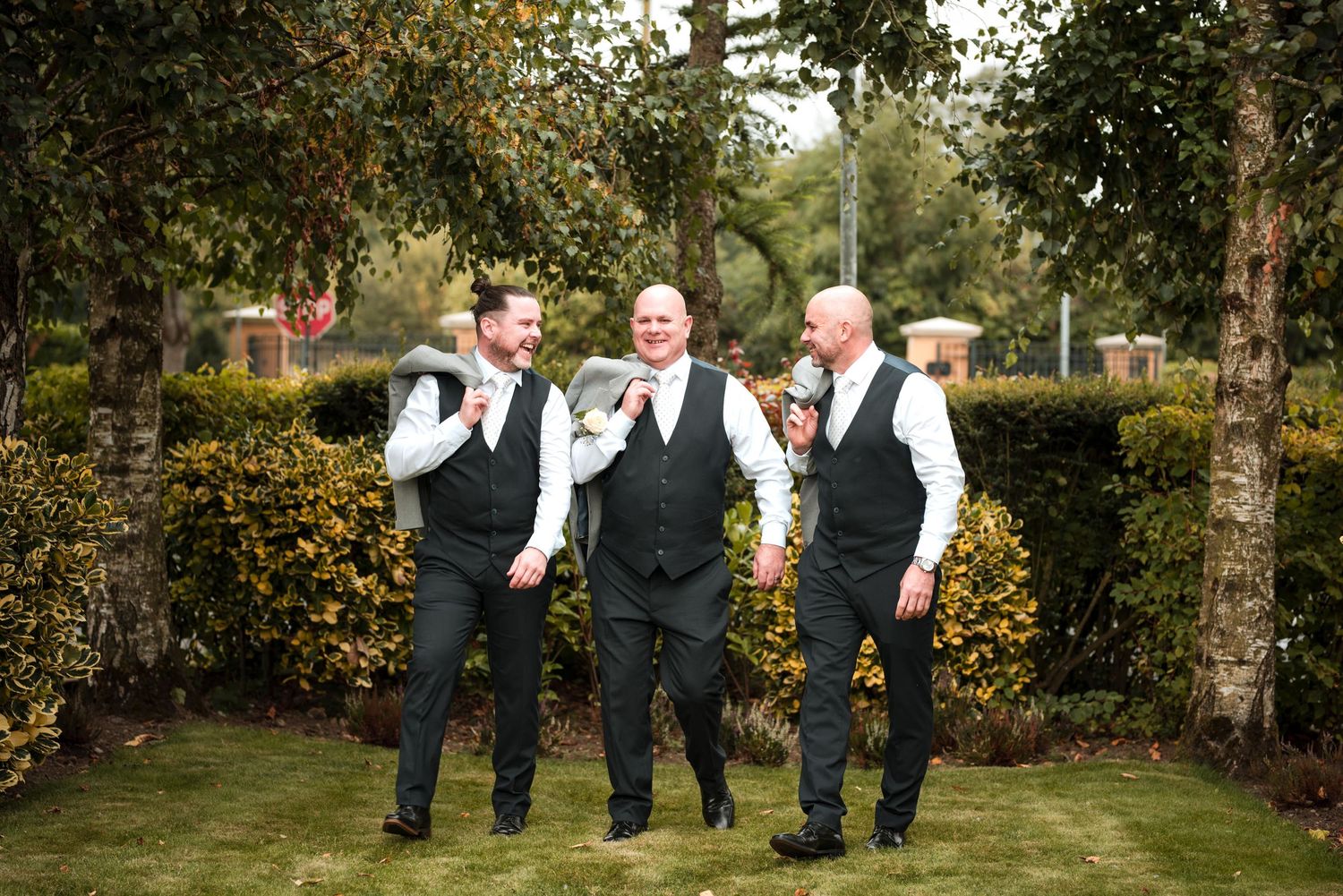 Wedding party group sharing a candid moment of laughter together in a lush garden setting.